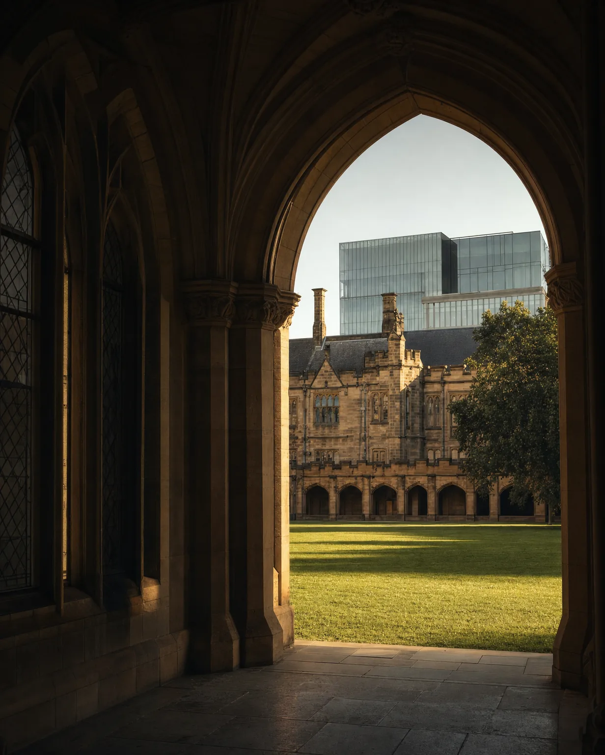 A sandstone university quadrangle opening onto a modern research building